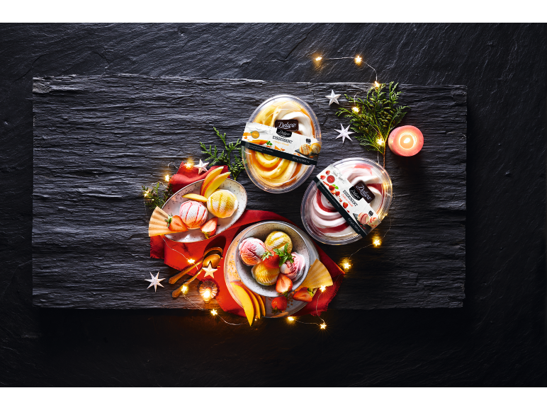 Ice cream desserts with fruit, festive decorations, and fairy lights on a dark slate background.