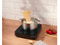Induction hob with a pot of boiling water and spaghetti on a wooden countertop.