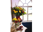 Autumn bouquet of yellow, orange, and red flowers on a wooden table in front of a window.