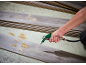 Hand cleaning sawdust from wood planks with a compressed air gun.