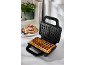 Waffle maker with freshly baked waffles and a plate of waffles with berries.