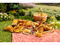 Picnic with a variety of pastries, berries, and drinks on a red checkered blanket.