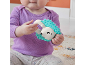 Baby holding a turquoise and white hedgehog rattle.