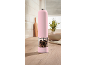 Pink electric pepper grinder with mixed peppercorns on a wooden kitchen counter.