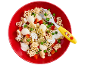 Kids' animal-shaped pasta with peas, bell peppers, and white sauce in a red bowl.