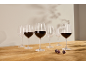 Wine glasses with red wine and empty glasses on a wooden table, with grapes.