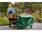 Woman covering garden furniture with a green tarp on a patio.