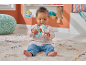 A baby sitting on a rug playing with a fox-shaped rattle toy.