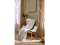 Cozy armchair with a white fluffy blanket in a living room with wooden furniture.