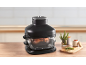 Black air fryer on a wooden table with rosemary and spices.