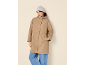Woman in a beige hooded coat, grey beanie, and blue jeans.