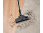 Vacuum cleaner head on a carpet and wooden floor with dirt