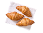 Three golden-brown croissants on a white napkin, viewed from above.