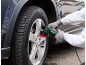 Person polishing a car wheel rim with an electric tool.