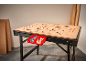 A workbench with a perforated wooden top, holding two red bins with screws and wooden dowels.
