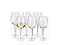 Six wine glasses, one filled with white wine, on a black background.