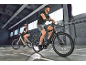 Two cyclists on electric bikes indoors, ready to ride.