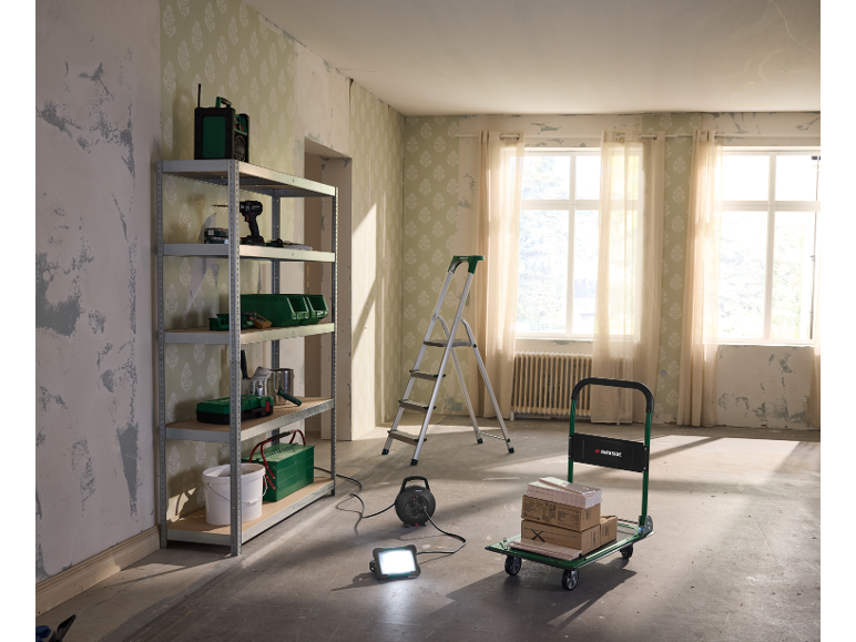 Shelving unit with tools, hand truck, and ladder in a room under renovation.