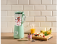 Mint green blender with berries and yogurt, and fresh fruit on a wooden table.