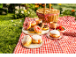Donuts of various flavors and strawberries at a picnic with a basket and checkered blanket.