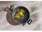 Frying pan with vegetables: broccoli, corn, snap peas, and berries on a grey background.