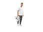 Man in white t-shirt and grey sweatpants holding a portable pedal exerciser.