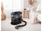 Carpet cleaner with hose and nozzle on a light rug in a cozy living room.