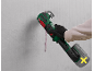 Cordless multi-tool with a grout accessory, being used on a wall.