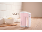 Pink hand mixer on a kitchen counter with eggs and a bowl of flour.