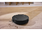 Black robot vacuum cleaner cleaning dirt on a wooden floor.