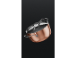 Copper cooking pot with a shiny lid and handles on a dark background.