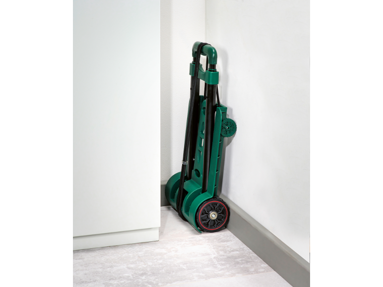 Foldable hand truck with elastic straps, stored upright in a corner.
