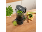 Black juicer with cucumber, celery, and basil on a wooden countertop.