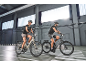 Man and woman cycling on electric bikes indoors.