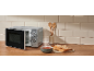 Open microwave, bowl of soup, and bread on a wooden countertop.