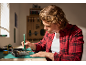 Man repairing an electronic device with an electric screwdriver on a cutting mat.