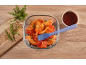 Raw chicken wings in a glass dish with a basting brush, sauce, and rosemary sprigs.