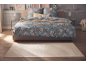 Bedroom with double bed featuring blue floral bedding and a light rug.