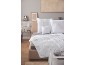 Bed with white quilted duvet and pillows, with a bedside table next to it.