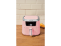 Pink air fryer on a wooden table with tiled background and fries.