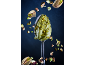 Spoon with pistachio cream and floating pistachios against a dark background.