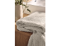 Folded grey bath towels on a wooden cabinet with a green plant.
