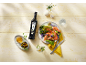 Bottle of olive oil, shrimp salad, and olives on a light wooden table.