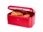 Red bread bin with an open lid and golden croissants inside.