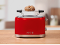 Red toaster with a bread roll on the warming rack, on a wooden table.