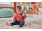Baby sitting on a rug, playing with a blue and colorful rattle.