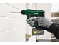 Gloved person drilling into a white brick wall with a cordless drill.