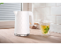 White hexagonal pattern kettle and steaming mint tea cup on a wooden countertop.