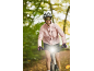 Woman on a bike with a helmet and sunglasses, the bike's front light is on.