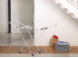 White clothes drying rack with laundry basket and red candles in a modern interior.